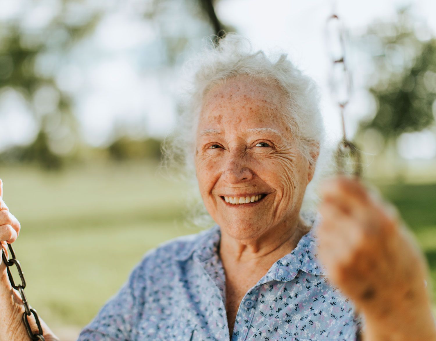 Elderly Woman on sitting on a swing smiling